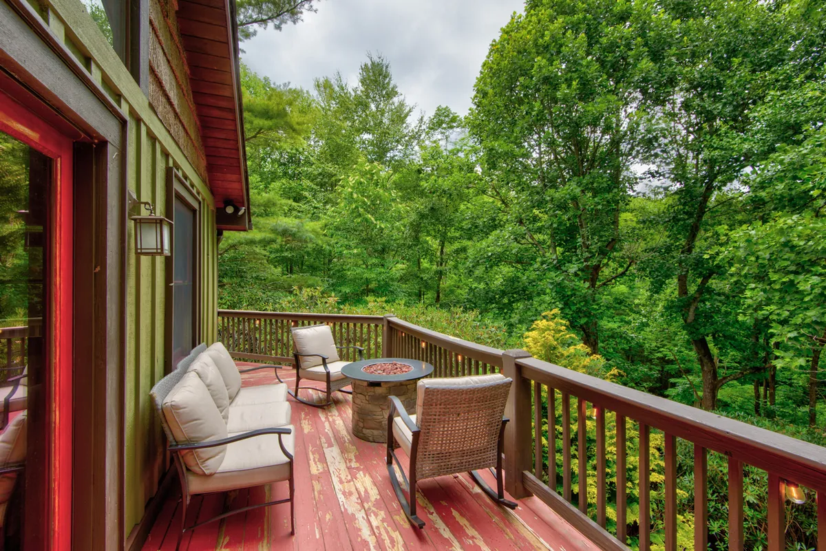 A peaceful backyard scene featuring outdoor seating arranged around a fire pit, surrounded by lush foliage and greenery. The area feels secluded and ideal for relaxation or sharing stories after a day spent on the trails.